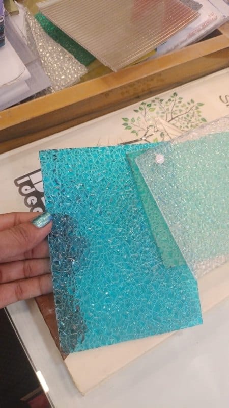 Turquoise-blue polycarbonate diamond sheet sample with diamond texture, hand-held with other samples.