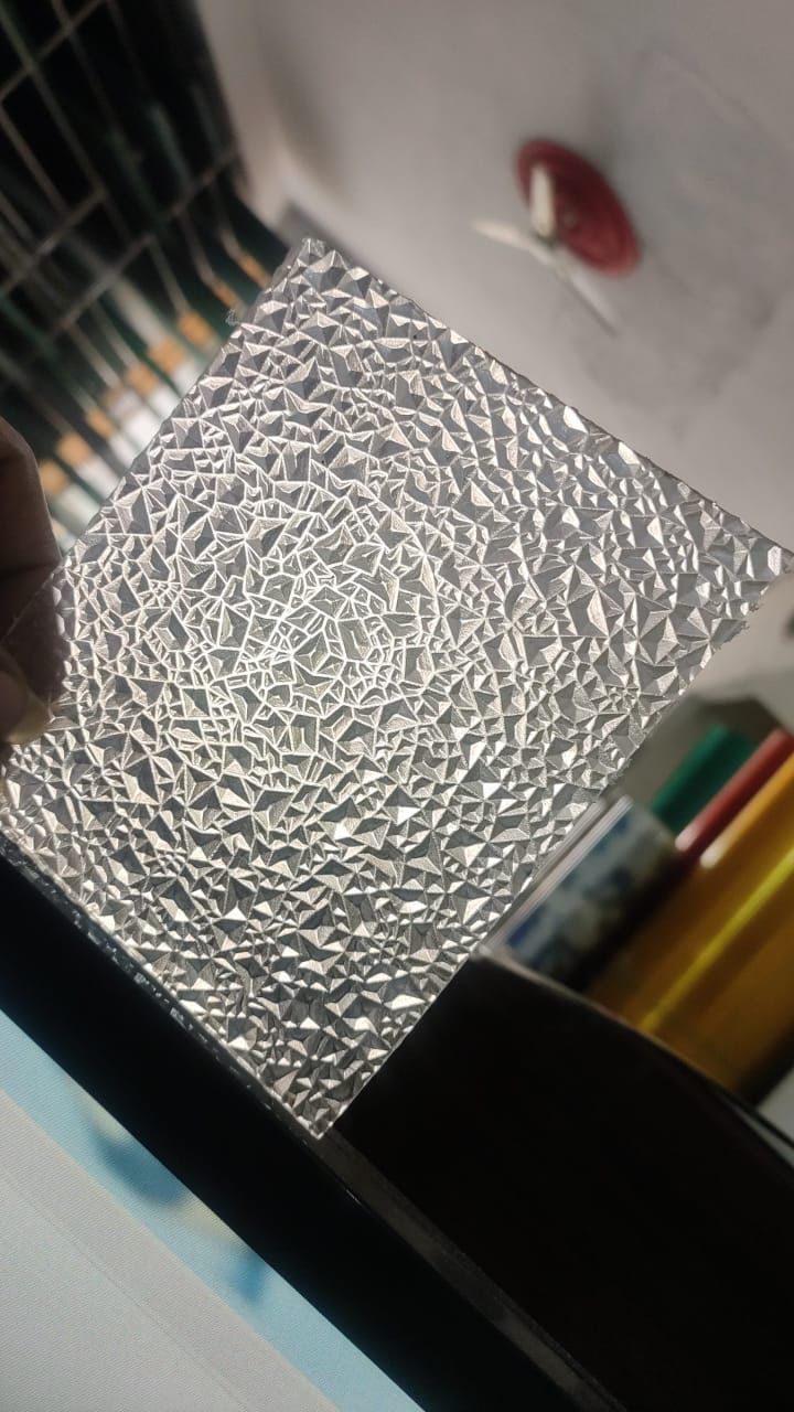 Clear textured polycarbonate diamond sheet held up, showing faceted diamond pattern and light diffusion.