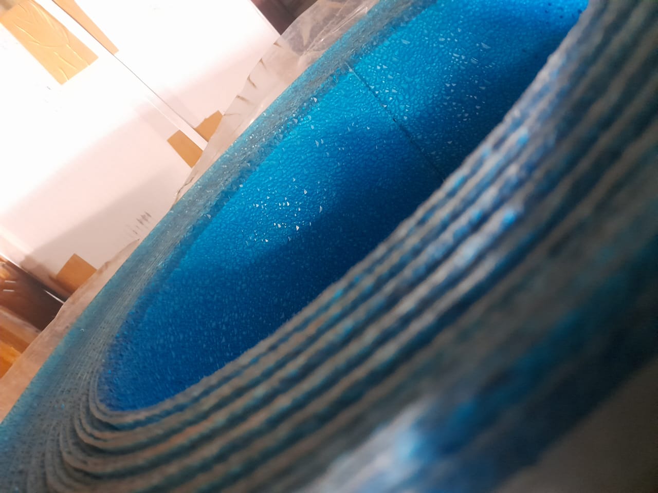 Rolled blue polycarbonate diamond sheet showing textured surface and corrugated edge profile.