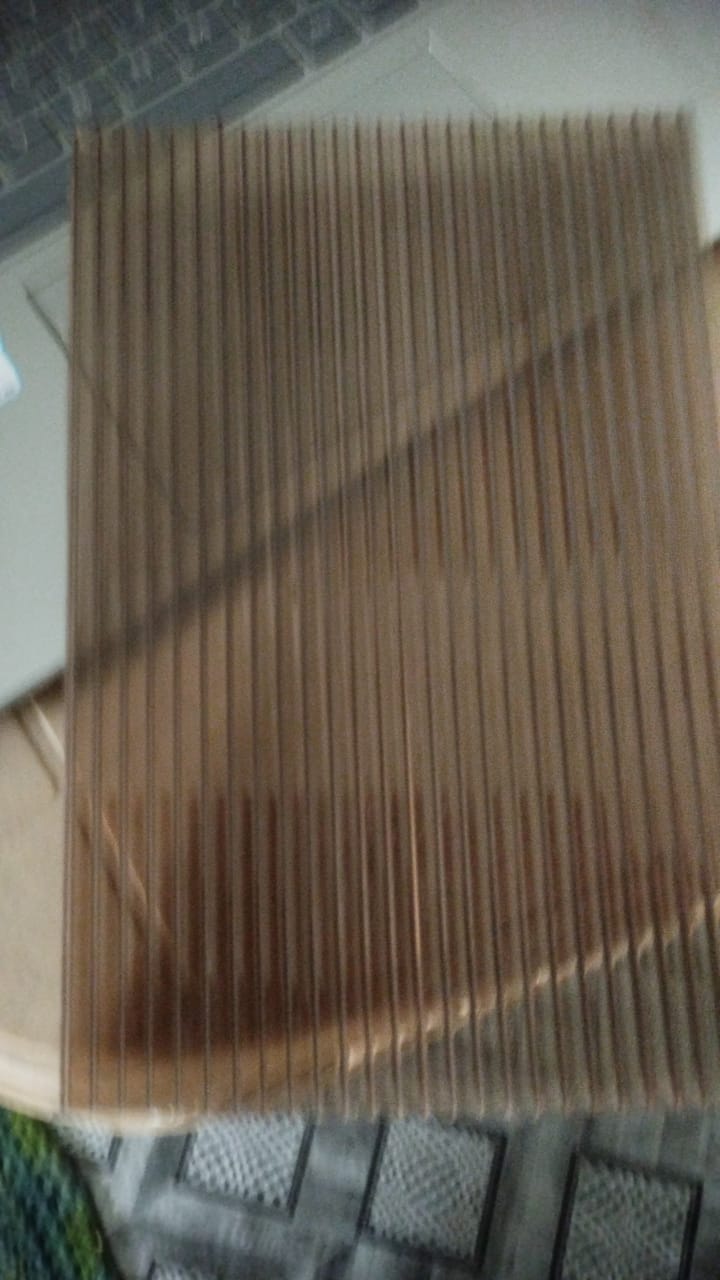 Close-up of translucent bronze-tinted polycarbonate multiwall sheet showing fluted structure.