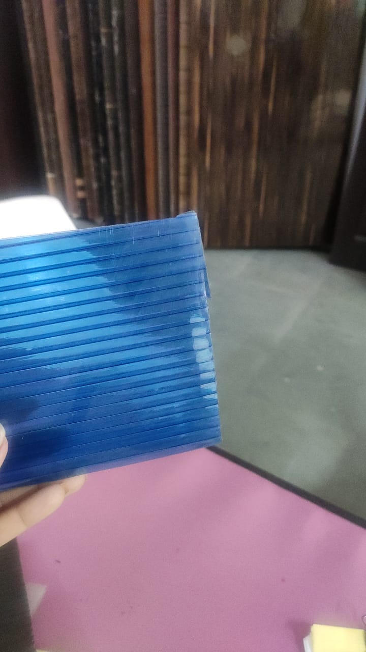 Translucent green multiwall polycarbonate sheet held vertically, showing ribbed structure.