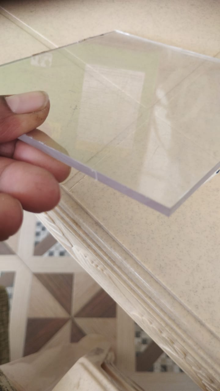Hand-held clear polycarbonate solid sheet showing edge detail and uniform thickness.