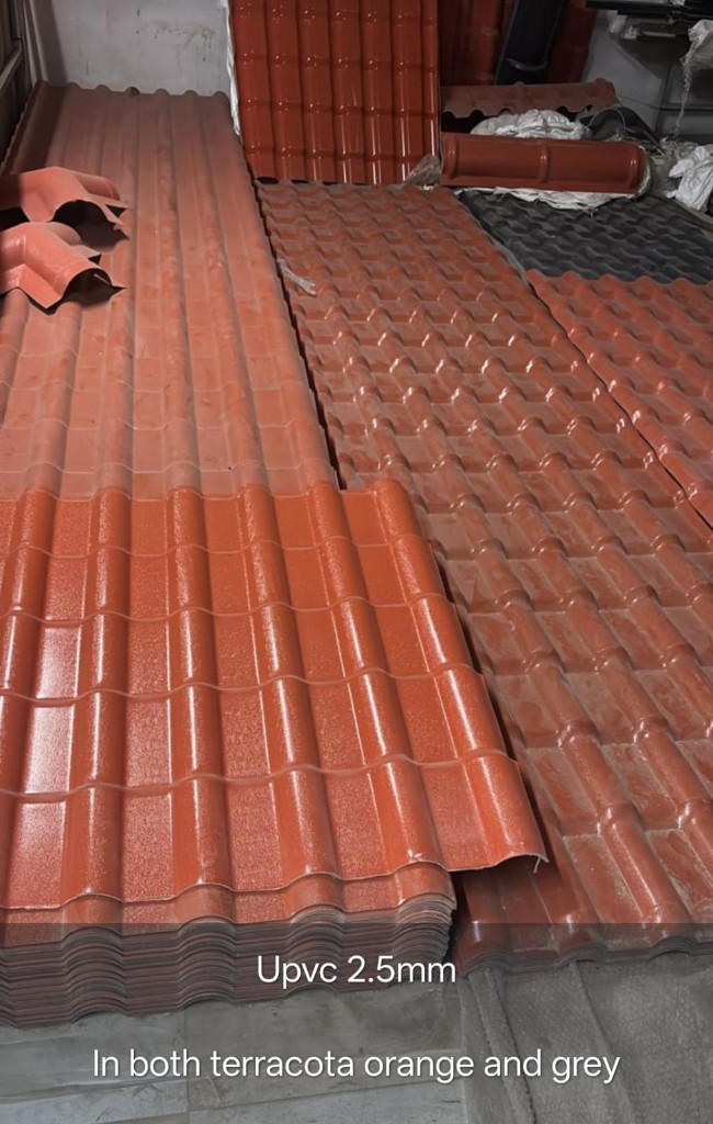 Stacked UPVC tiled sheets in terracotta and grey colors, 2.5 mm thick profiles ready for dispatch and site installation.